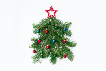 Stylized Christmas tree made of fir tree branches and ball toys on marble background. New Year and Christmas celebration concept. Flat lay, top view.