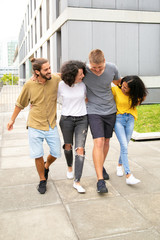 Happy excited close friends hanging out together outside. Young mix raced people walking, hugging each other, laughing and having fun. Hangout together concept