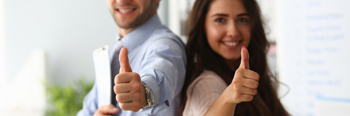Businessman and business woman hold thumbs up