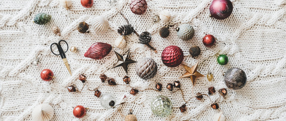 Christmas or New Year holiday background, texture, wallpaper. Flat-lay of Christmas glass festive decoration toys and balls over white knitted woolen background, top view, wide composition