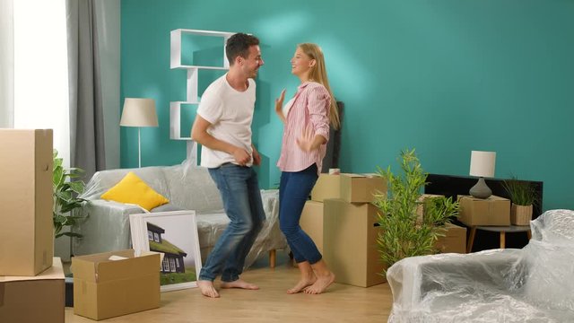 Young couple have fun dancing in their new apartment