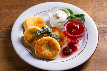 Cottage cheese pancakes. Syrniki with fresh mint, sour cream and strawberry jam, ice cream - dessert concept