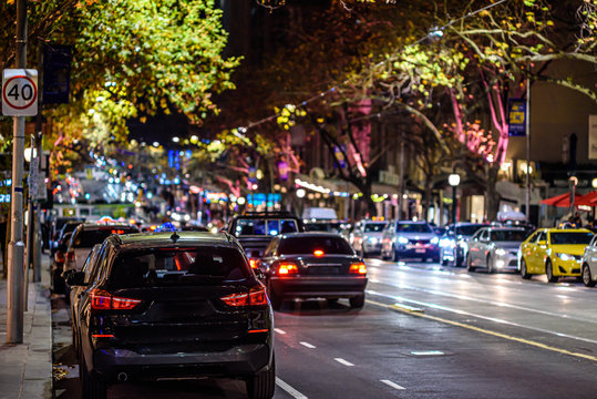 A Downtown City Street In Melbourne Australia At Night, Showing City Lights, Traffic And Tram Tracks