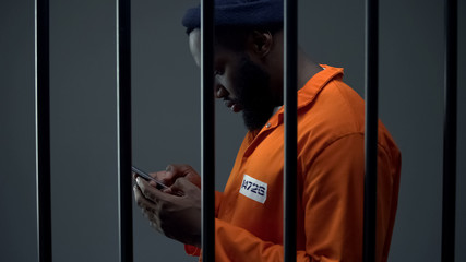 Afro-american prisoner using phone in cell, corruption in prisons, prohibition