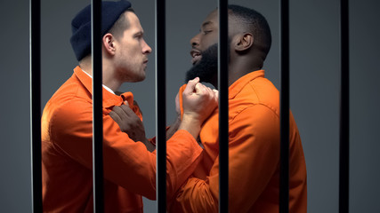 Black and caucasian prisoners having fight in cell, jail overcrowding, conflict