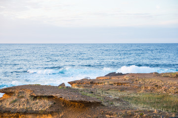 Fototapeta na wymiar Waves crashing into the rocks on a summer evening.