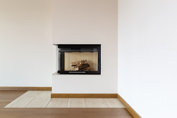 Detail of fireplace with wooden logs and white wall