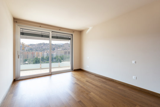 Empty room with parquet flooring and large window