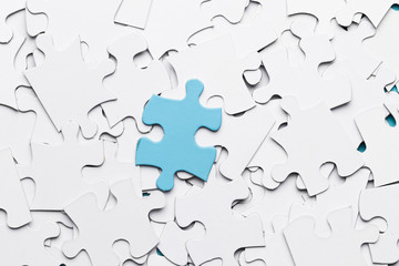 Blue jigsaw puzzle piece over white puzzle pieces