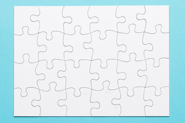 Elevated view of white jigsaw puzzle grid on blue surface