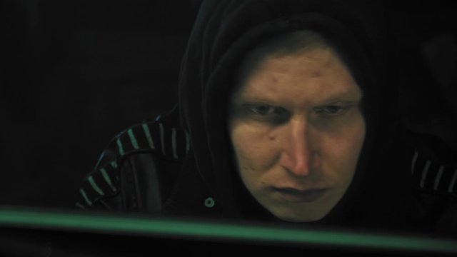 Male hacker working on a computer for cyber attack his face in a dark office room in 4k