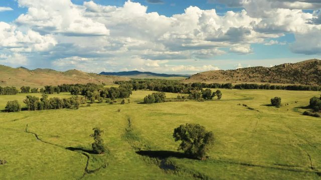 Aerial view of a beautiful grass valley with a small creeks and mountains in the background. Wyoming, USA | 4K
