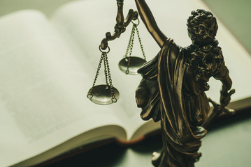 Figure of Justice standing over a law book