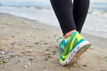 Athletic woman running on sea beach, closeup. Female runner working out at summer morning, copy space. Healthy lifestyle concept