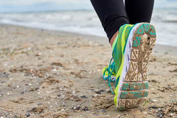 Athletic woman running on sea beach, closeup. Female runner working out at summer morning, copy space. Healthy lifestyle concept