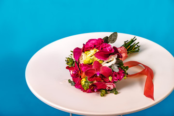 Beautiful bouquet of flowers on white round table on blue background.