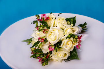 Beautiful bouquet of flowers on white round table on blue background.