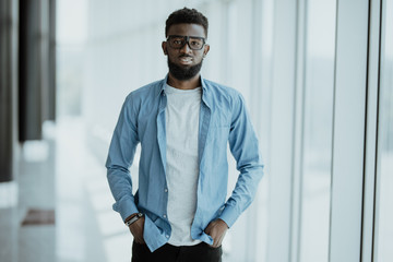Handsome African American man standing near panoramic windows in office center