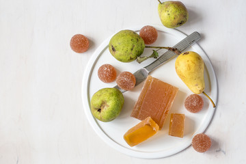 Homemade fruit marmalade and fresh pears on a round white dish on a light wooden background....