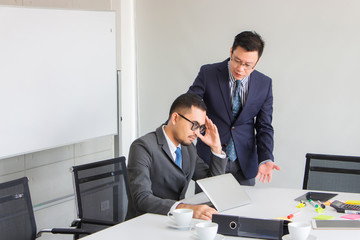A colleague is encouraging a friend with a sad face after he is blamed by a master who works wrong...