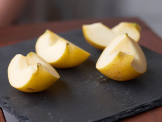 Slices of apple on stone plate on wooden table - breakfast with slices of apple - sliced golden apple