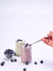 Women's hand holding a spoon with blueberry yogurt