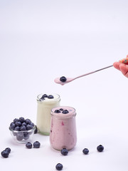 Women's hand holding a spoon with blueberry yogurt