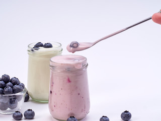 Women's hand holding a spoon with blueberry yogurt