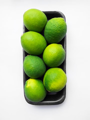 green limes in a black substrate on a white background, top view