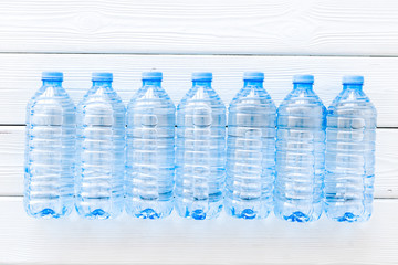 Plastic bottles with pure water on white wooden background top view