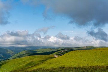 Beautiful view of idyllic alpine mountain scenery with blooming meadows and mountains on a beautiful sunny day with blue sky and clouds in summer.