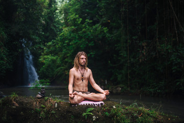 Yoga practice and meditation in nature. Man practicing near river