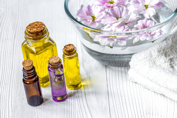flowers in bowl and oil on wooden background