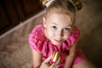 Blonde brown-eyed girl eats sweet biscuit