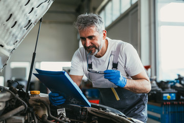 Fototapeta na wymiar mechanic looking at parts brochure in car service