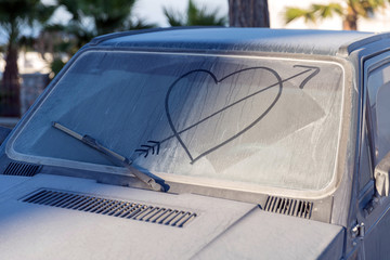 Dirty car window with drawn heart and arrow on it