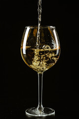 White wine being poured in a wine glass on a dark background