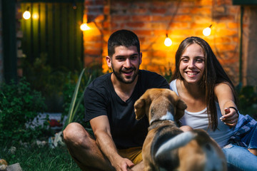 man and woman playing with dog outdoor