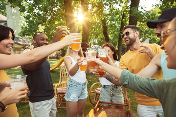 Group of happy friends having beer and barbecue party at sunny day. Resting together outdoor in a...
