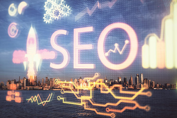 SEO hologram on city view with skyscrapers background double exposure. Search optimization concept.
