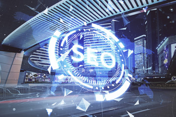 SEO hologram on city view with skyscrapers background double exposure. Search optimization concept.