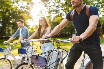 Group of happy friends riding bicycles at the park