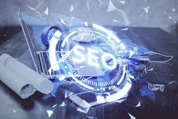 Double exposure of table with computer and seo drawing hologram. Search optimization concept.
