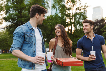 Group of cheerful young friends walking at the city streets