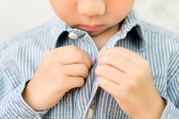 Child Development concept: Close up of a little kindergarten boy's hands learning to get dressed,...