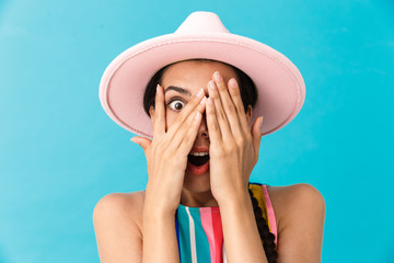 Image closeup of excited caucasian woman wearing hat covering her face and looking at camera