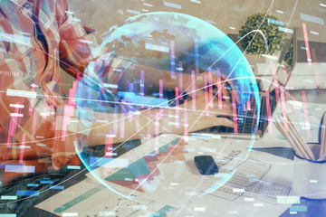 Double exposure of stock graph with businessman typing on computer in office on background. Concept of hard work.