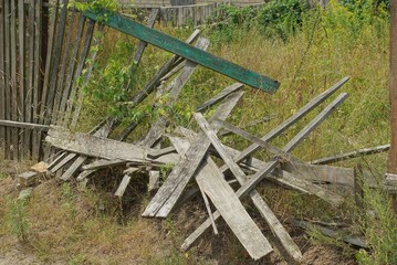 gray broken wooden plank fence in green grass 