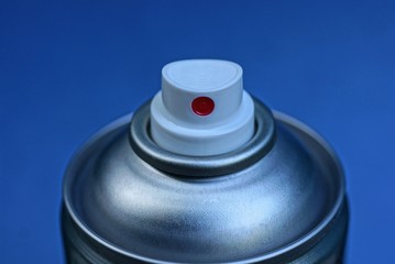 gray metal spray can with white plastic dispenser on a blue background