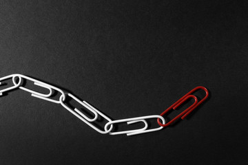 Leadership concept with paper clips on a dark background.One leader paper clip leads other clips